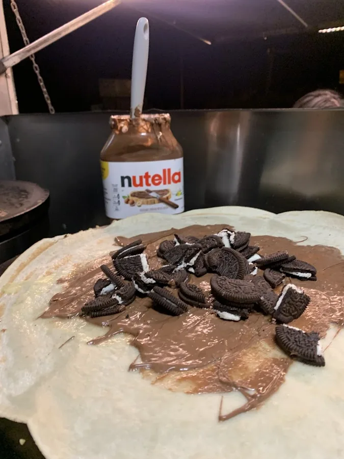 Crêp'île, crêpe Nutello garnie de Nutella fondu et d'éclats d'Oréo sur la plaque